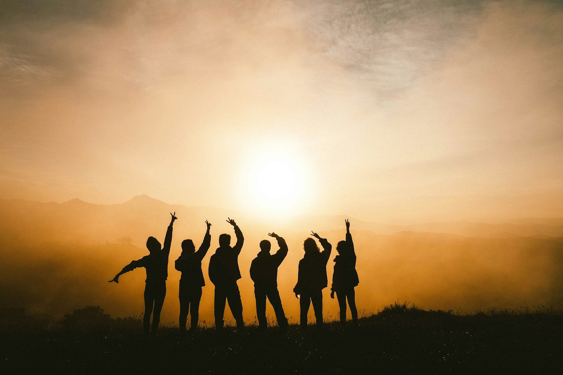 Friends silhouetted on a hilltop at sunrise